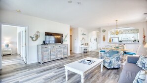 A spacious living room with a large TV, a white coffee table, and a patterned sofa. - 1521 Ironwood - Barefoot Resort Rentals (North Myrtle Beach)