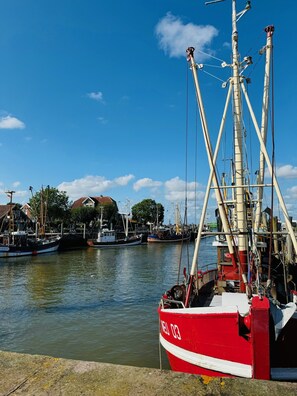 A harbor with boats docked, a clear sky, and buildings in the background.