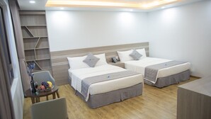 A hotel room with two beds, a small table with a vase and fruit, and a chair. - Bamboo Hotel (Sam Son)