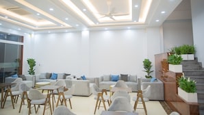 A modern lounge area with sofas, chairs, and a staircase with plants. - Bamboo Hotel (Sam Son)