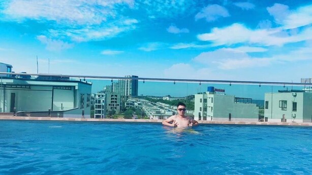 A swimming pool with a cityscape view, modern buildings, and a clear sky. - Bamboo Hotel (Sam Son)