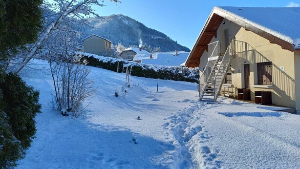 A snow-covered landscape with a building featuring a wooden staircase and a view of a mountain. - Pretty Private Studio surrounded by mountainous nature. Pets Allowed (Coyrière)