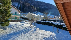A snow-covered residential area with houses, a pine tree, and a mountain in the background. - Pretty Private Studio surrounded by mountainous nature. Pets Allowed (Coyrière)