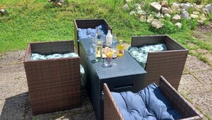 A picnic setup with wicker tables and benches, a bottle of water, and a glass of juice. - Pretty Private Studio surrounded by mountainous nature. Pets Allowed (Coyrière)