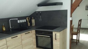A modern kitchen with a black countertop, wooden cabinets, a built-in oven, and a skylight. - Pretty Private Studio surrounded by mountainous nature. Pets Allowed (Coyrière)