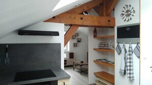 A modern kitchen with a black countertop, wooden beams, and a wall-mounted clock. - Pretty Private Studio surrounded by mountainous nature. Pets Allowed (Coyrière)