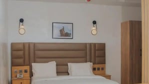 A bedroom with a bed, bedside tables, a chair, a small table, and a wardrobe.