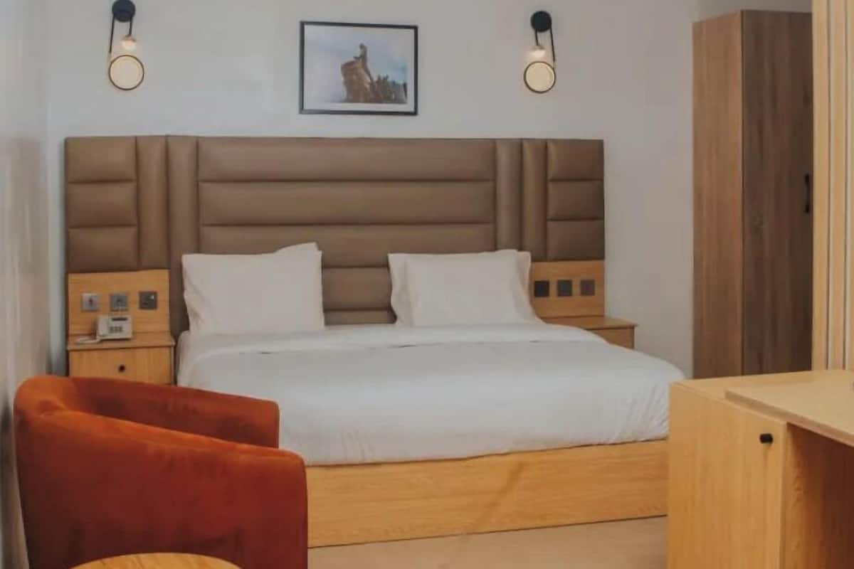 A bedroom with a bed, bedside tables, a chair, a small table, and a wardrobe.