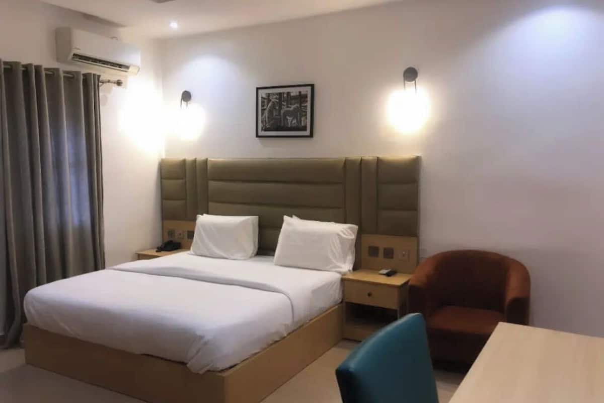 A hotel room with a large bed, bedside tables, a chair, and a table.