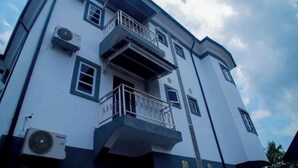 A multi-story building with balconies, air conditioning units, and a clear sky.