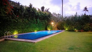 A swimming pool surrounded by well-maintained grass and dense foliage. - South Point Surf House - Whole Villa 5 Bedrooms (Sleeps 14)  (Koggala)