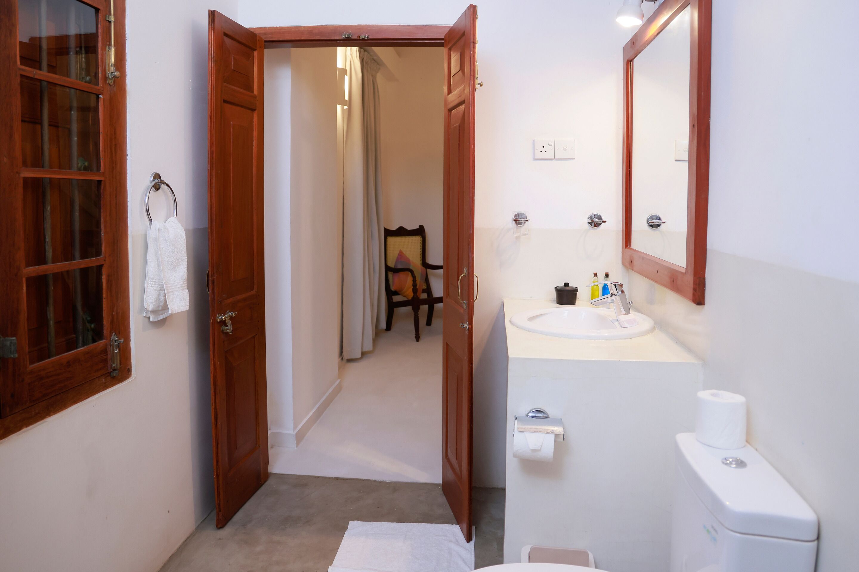 A bathroom with a wooden door, a white sink, a mirror, and a toilet.