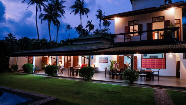 A two-story house with a covered patio, a swimming pool, and palm trees in the background. - South Point Surf House - Whole Villa 5 Bedrooms (Sleeps 14)  (Koggala)