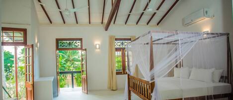 A bedroom with a wooden bed, a canopy, and a view of greenery through the windows.