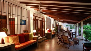 A covered outdoor seating area with a sofa, chairs, and tables, featuring a ceiling fan and a view of greenery. - South Point Surf House - Whole Villa 5 Bedrooms (Sleeps 14)  (Koggala)