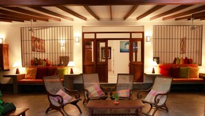A spacious lobby with a wooden ceiling, a central table, and seating areas with cushioned chairs and sofas. - South Point Surf House - Whole Villa 5 Bedrooms (Sleeps 14)  (Koggala)
