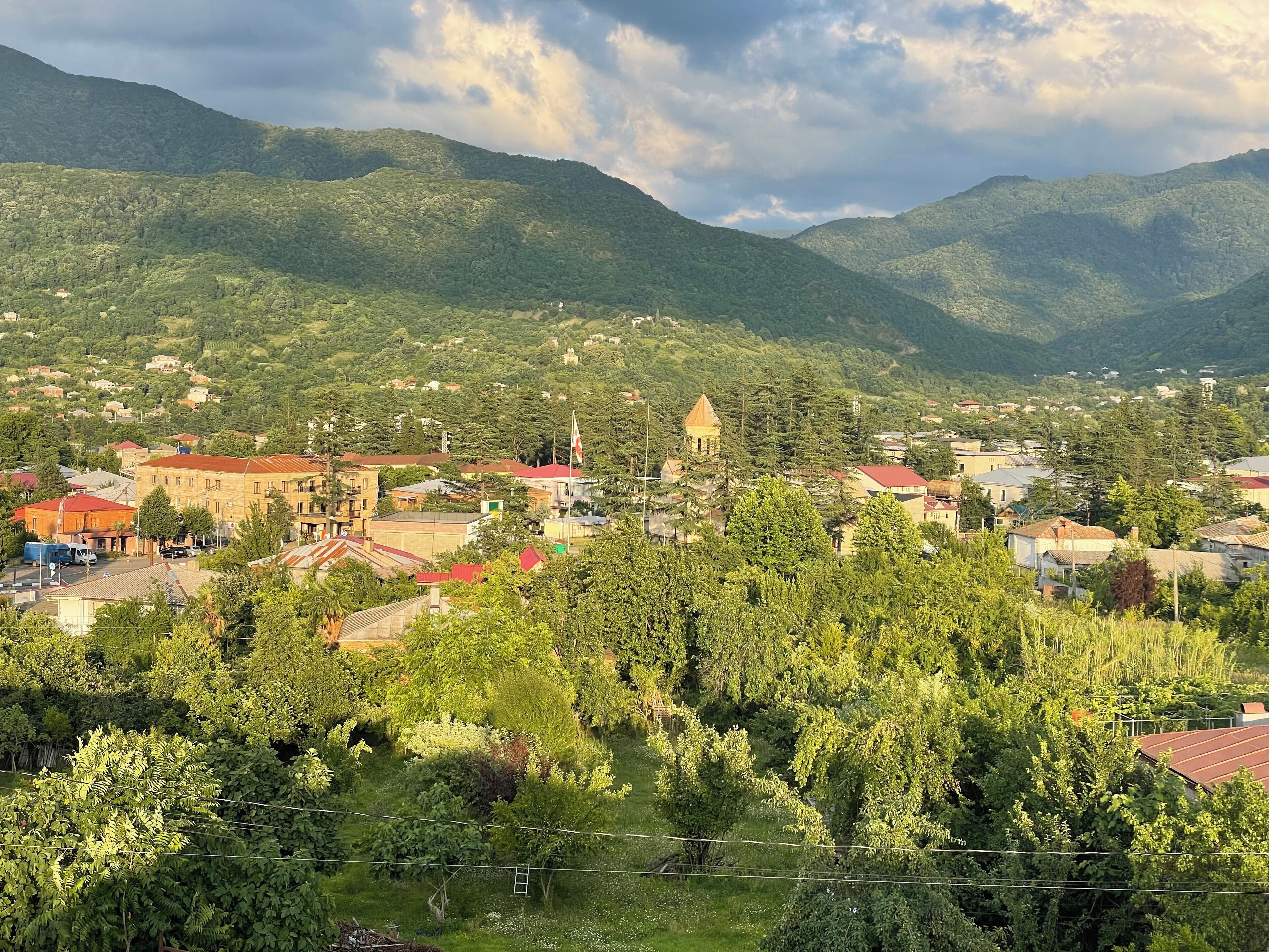 A town nestled in a valley with buildings, a prominent church, and surrounding mountains.