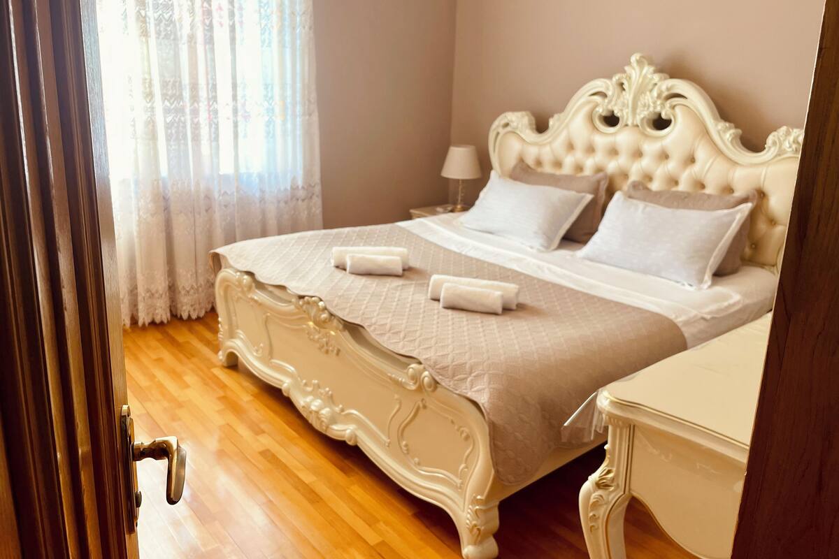 A bedroom with a large bed, a nightstand, and a door.