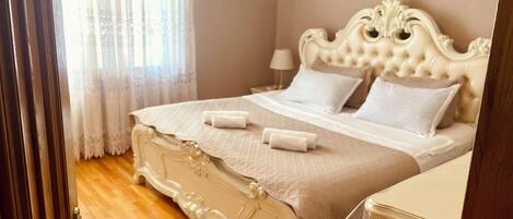 A bedroom with a large bed, a nightstand, and a door.