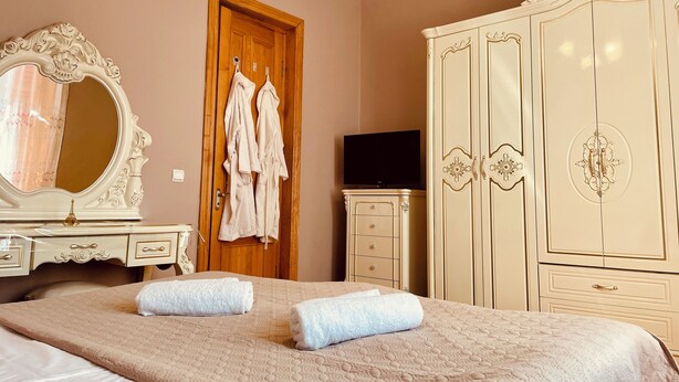 A bedroom with a large bed, a wardrobe, a television, and a mirror. - House of Warmth (Baghdati)