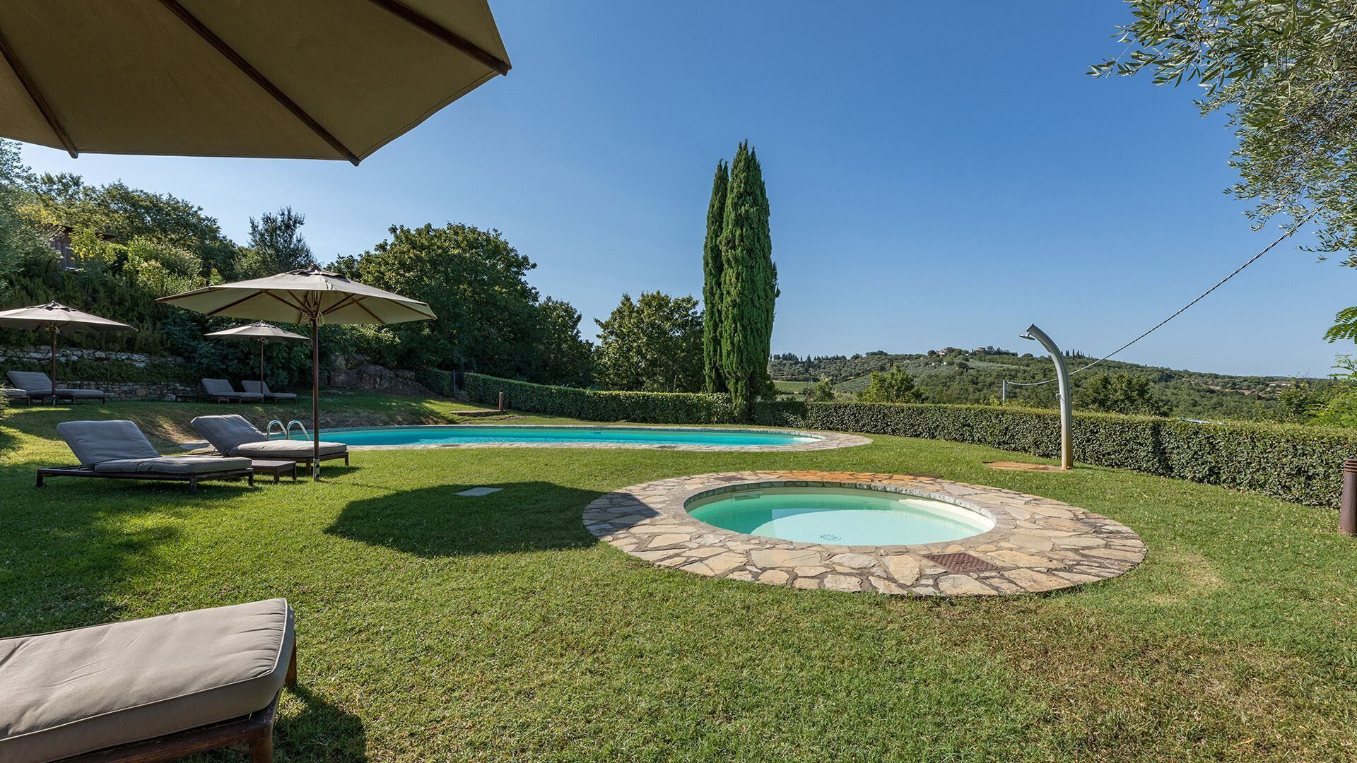 A backyard with a swimming pool, lounge chairs, and umbrellas.