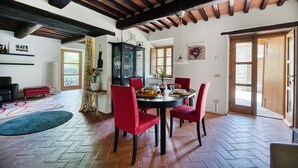 A dining area with a round table, red chairs, and a black cabinet. - Caravaggio, Galenda, Gaiole in Chianti, Siena and Chianti (Gaiole in Chianti)