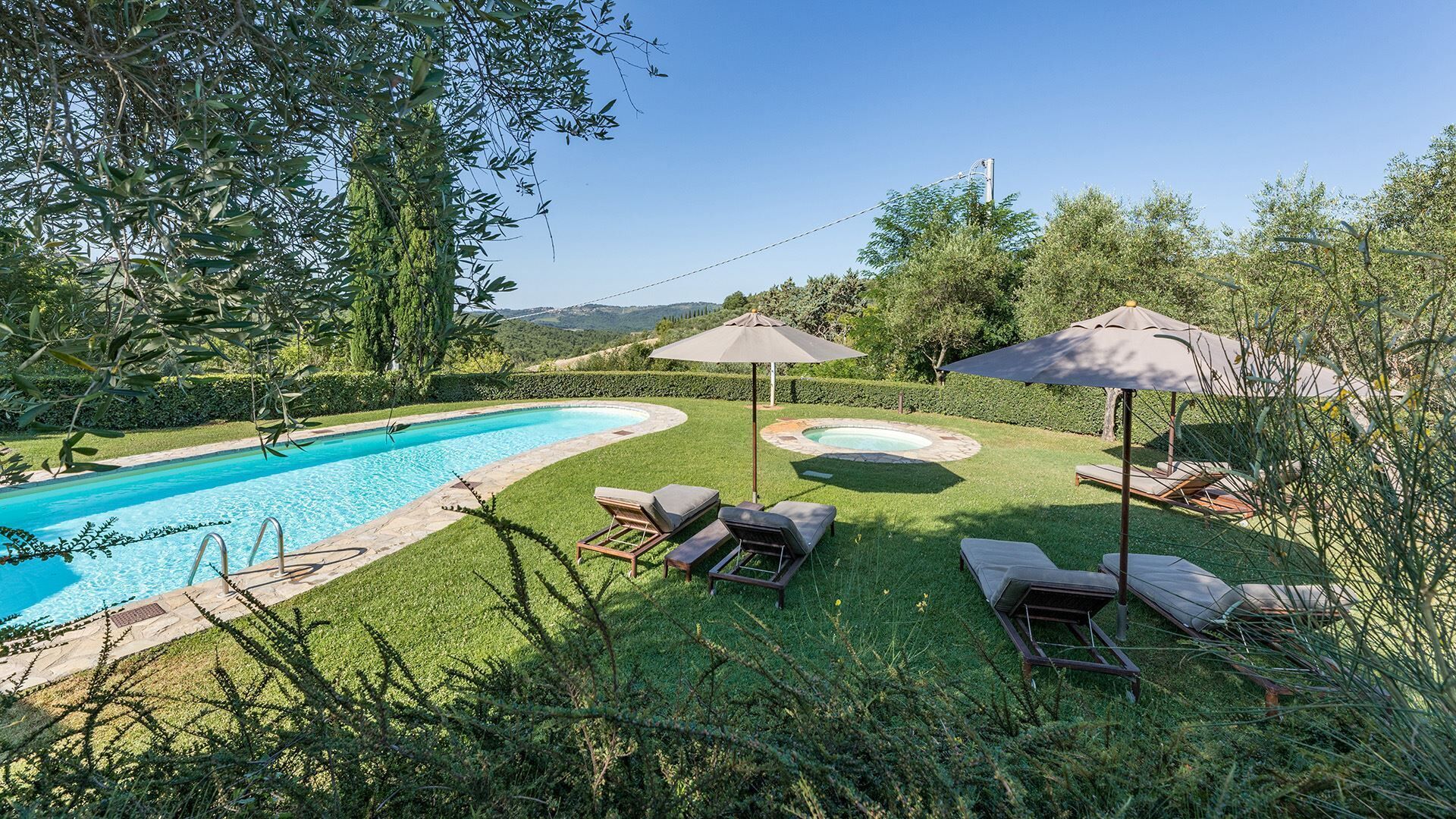 Un patio trasero con piscina, sillas de descanso y un jacuzzi.