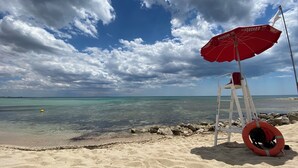 Ein Strand mit einer Rettungswache, einem roten Sonnenschirm und einem Rettungsreifen.