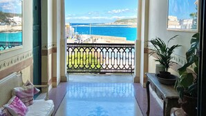 Ein Flur mit Meerblick, ein Balkon mit Geländer und ein Bett mit Kissen.