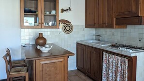 Eine Küche mit Holzausstattung, einer gefliesten Rückwand, einer Holzinsel, einem Stuhl und einem Gasherd.