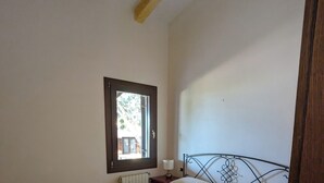 Ein Schlafzimmer mit einem Bett, einem Fenster, einer Heizung und einem Holzbalken an der Decke.