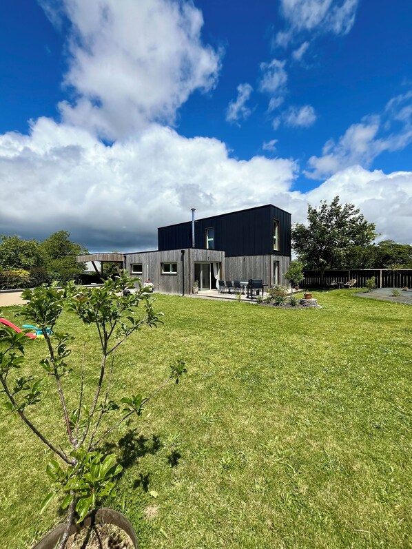 A modern two-story house with a flat roof, a chimney, and a covered patio area. - Maison en Bois , Ty Kérou (Mahalon)