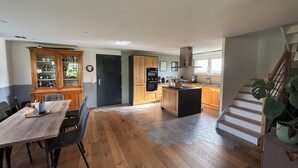 Una cocina amplia con armarios de madera, una isla central y un comedor con mesa y sillas de madera.