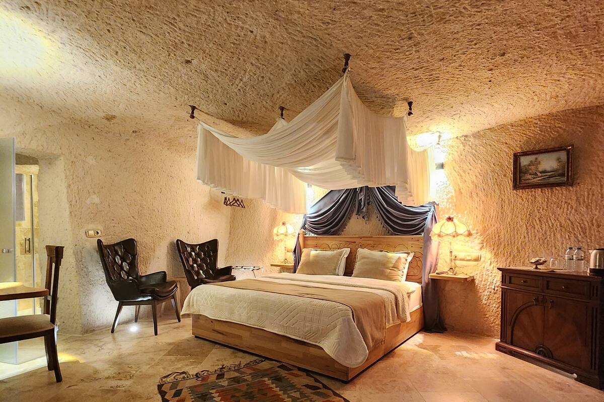 A bedroom with a large bed, a chair, a small table, and a rug.
