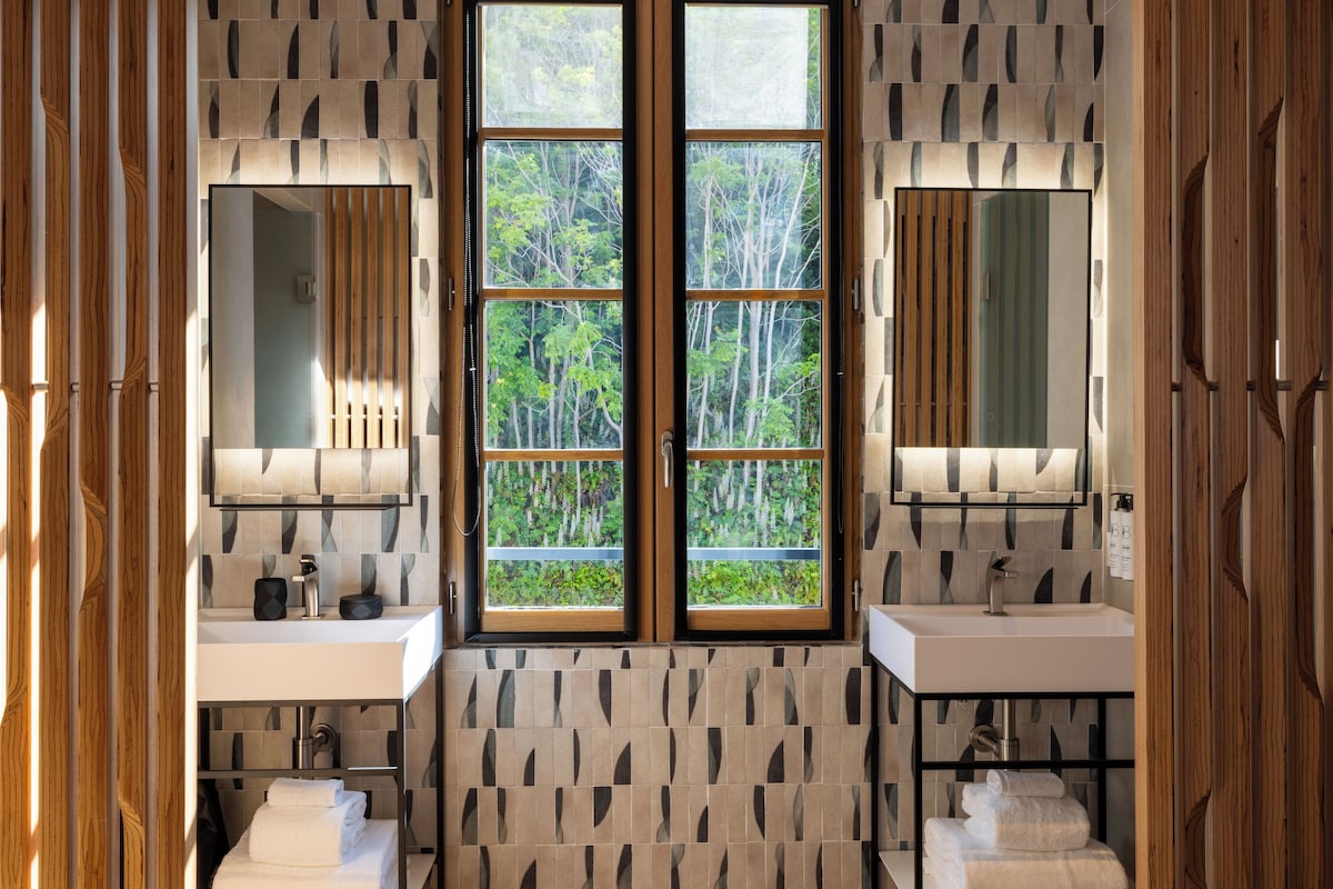 A bathroom with two sinks, a large window, and a patterned wall.