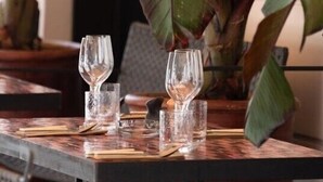A dining table with three wine glasses and cutlery, surrounded by chairs and a large potted plant. - Palais Ségurane Nice Boutique Hôtel (Nice)