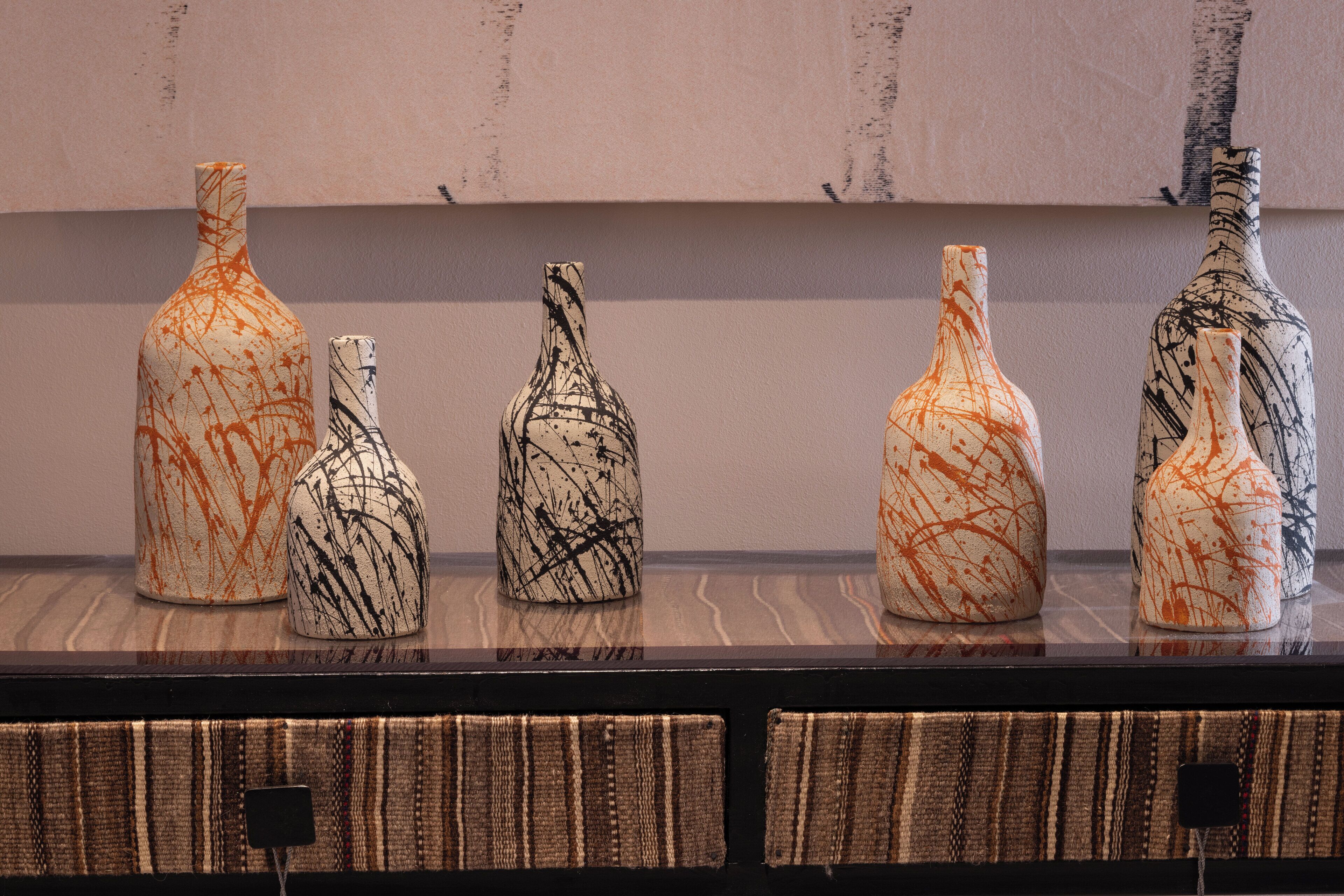 A display of five vases with abstract designs on a shelf.