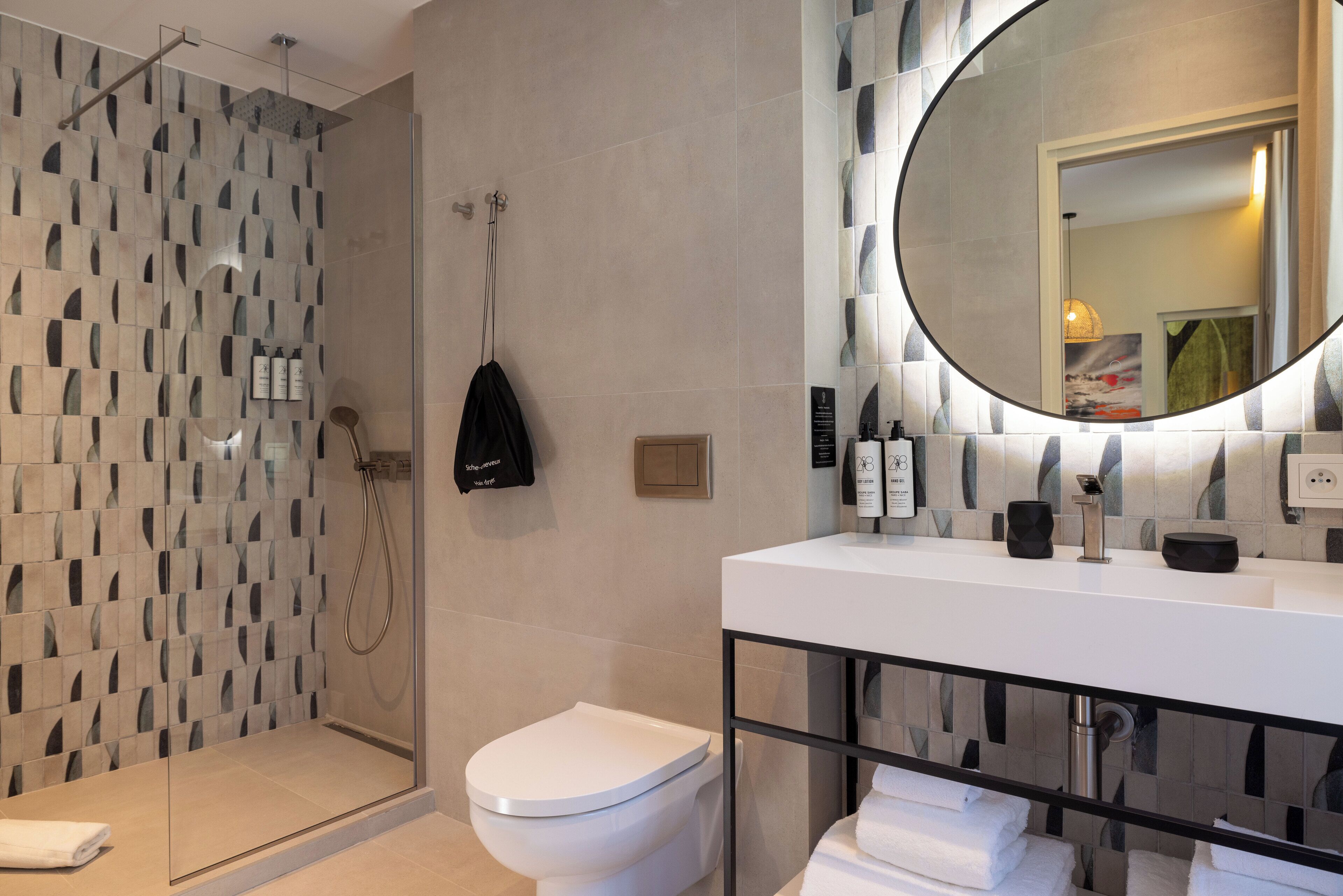 A modern bathroom with a glass-enclosed shower, a white toilet, and a large mirror above a white sink.