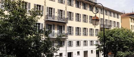 A multi-story building with balconies and a cobblestone street.