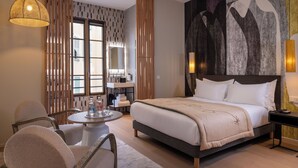 A modern hotel room with a large bed, a round dining table, and a seating area with chairs. - Palais Ségurane Nice Boutique Hôtel (Nice)