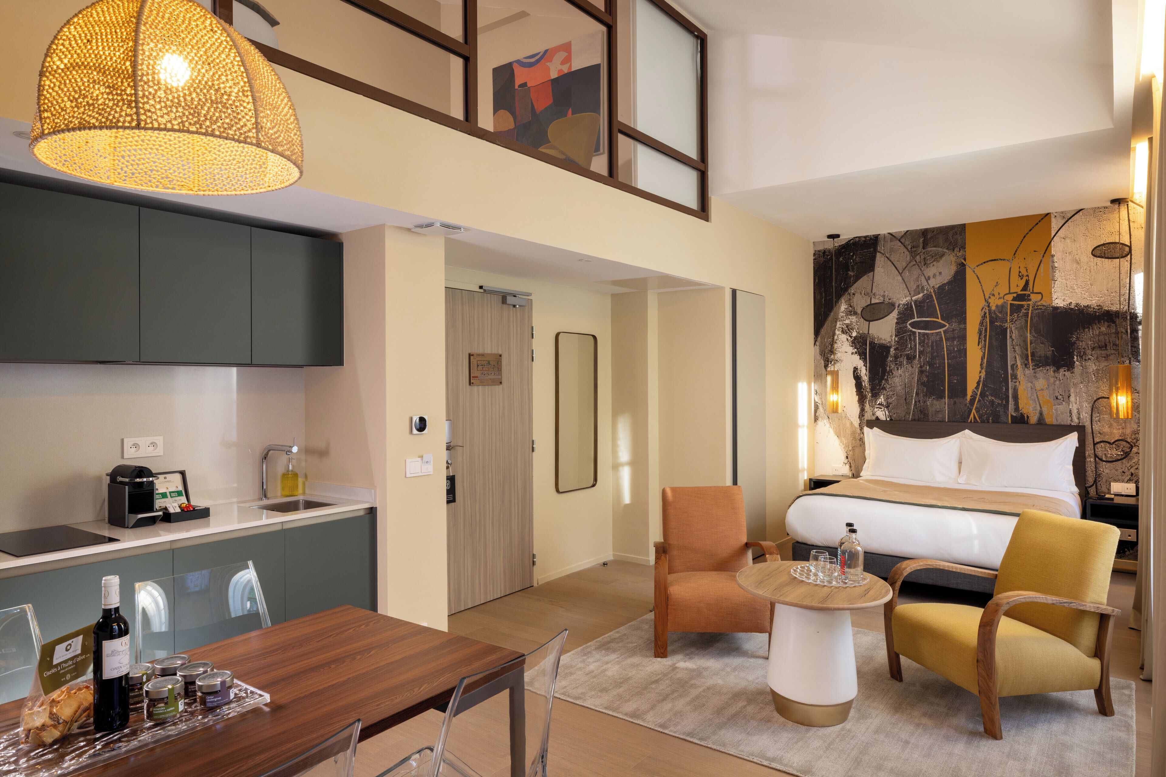 A modern hotel room with a kitchenette, a dining area, a sofa, and a bed.