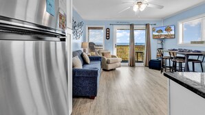 Una cucina moderna con frigorifero in acciaio inossidabile, un'area pranzo con tavolo e sedie, un divano blu e una ventola a soffitto.