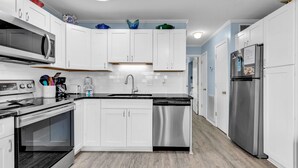 Una cucina moderna con mobili bianchi, elettrodomestici in acciaio inossidabile e pavimento in legno.