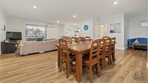 Un amplio salón con una mesa de comedor, sofás y una televisión.
