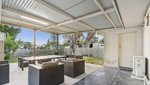 Un patio al aire libre con una zona de estar cubierta, que incluye sofás y una mesa.