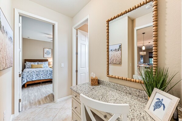 A bedroom with a bed, a bathroom with a sink and mirror, and a hallway leading to another room. - Newly furnished 3 bed 2 bath in beautiful Ole at Lely Resort in Naples Florida (Naples)