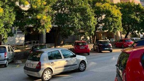 Un edificio a più piani con balconi e un’area di parcheggio con auto.