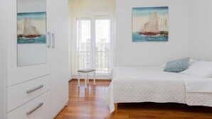 Una camera da letto con un letto, una sedia, un armadio e due quadri raffiguranti barche a vela.