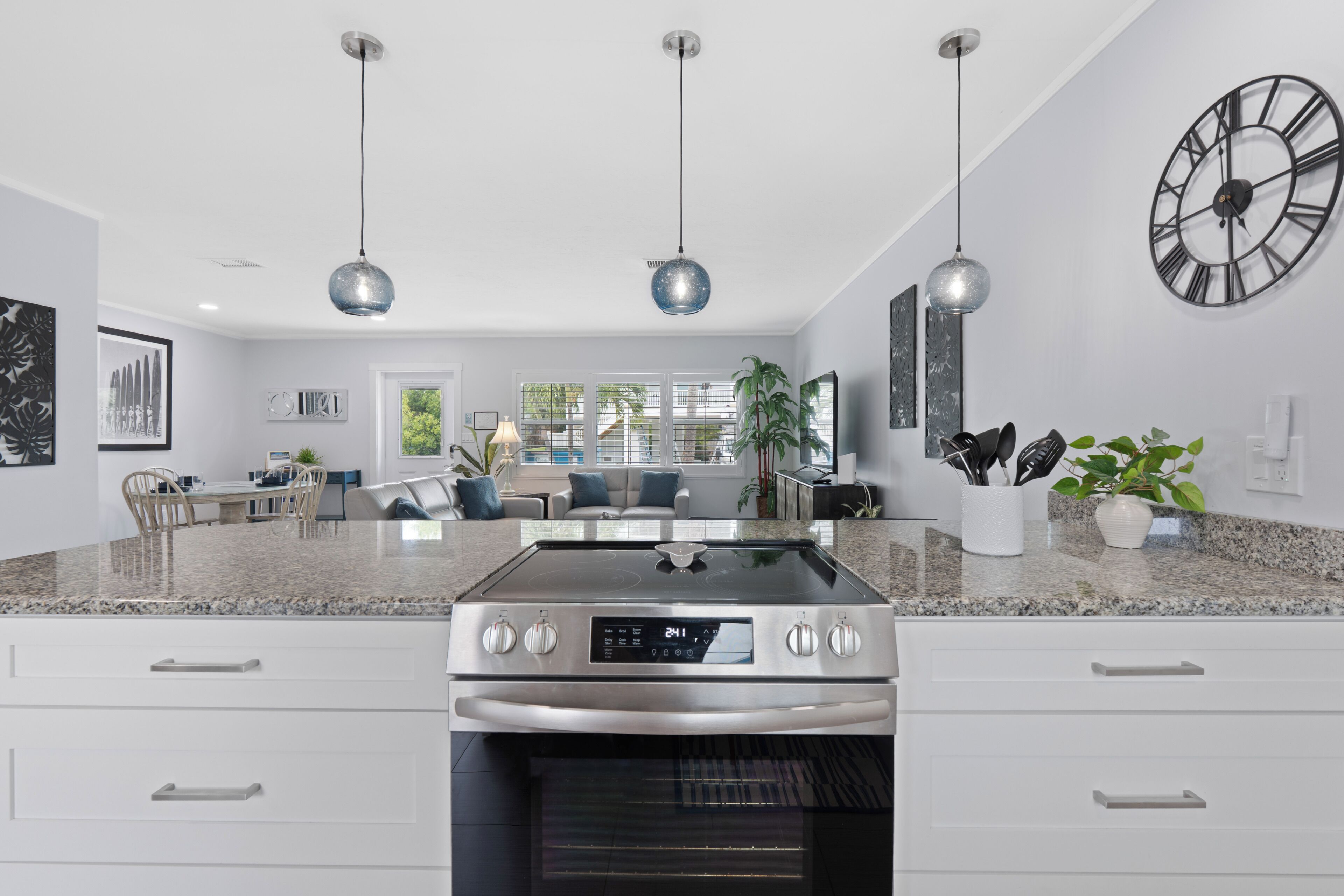 A modern kitchen with a built-in oven, a dining area with a sofa and chairs, and pendant lighting.