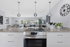 Una cocina moderna con horno empotrado, comedor con sofá y sillas, e iluminación colgante.
